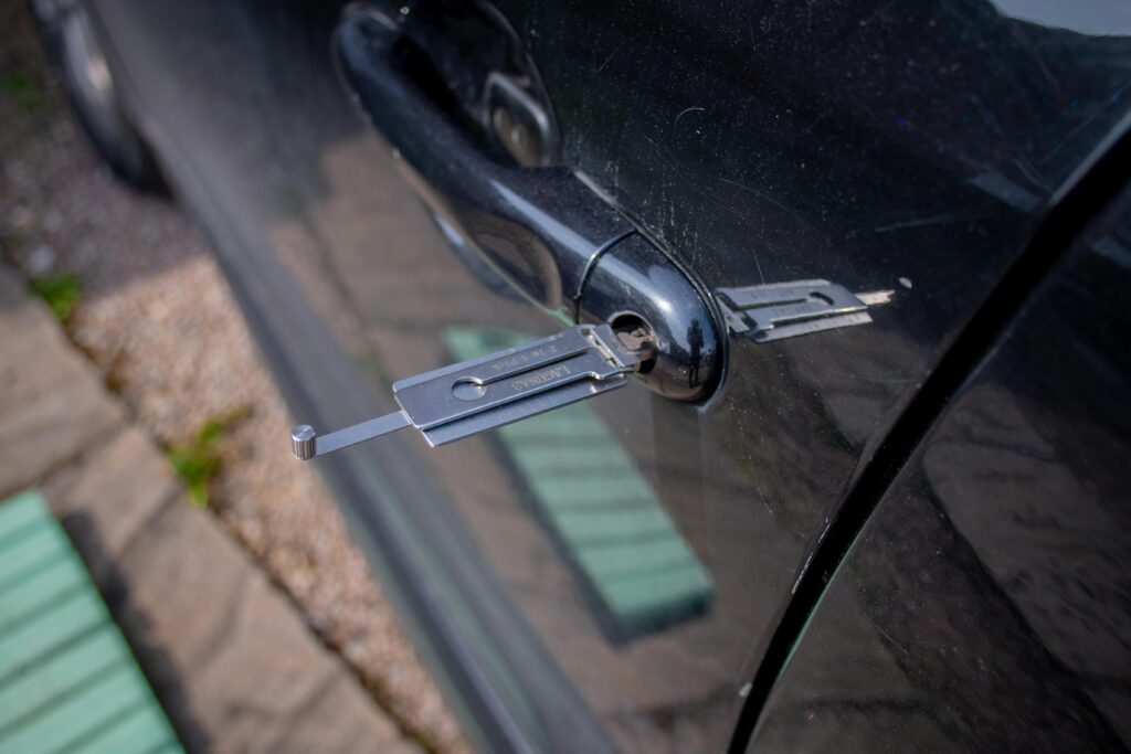 pexels photo 17124737 17124737 Close-up of a locksmith tool inserted into a car door lock, demonstrating security access.