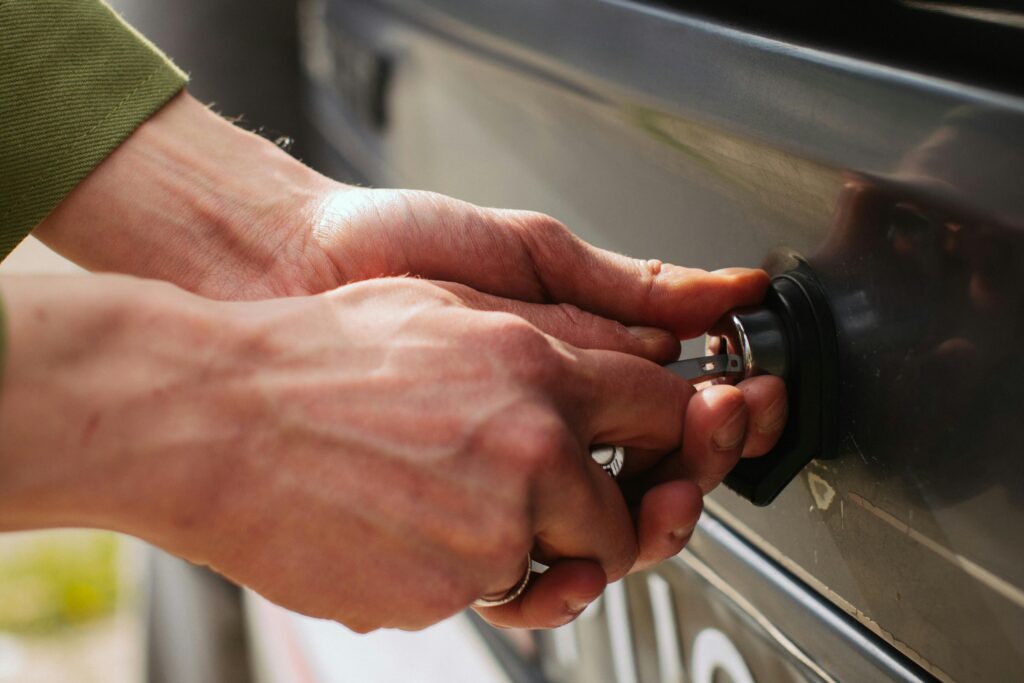 pexels photo 8103920 8103920 Close-up of hands unlocking a vehicle trunk with a key, showing detail and reflection.
